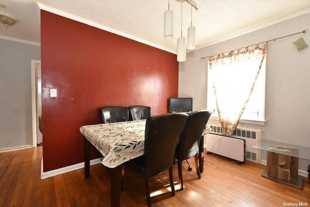 dining area featuring radiator, wood-type flooring, and ornamental molding