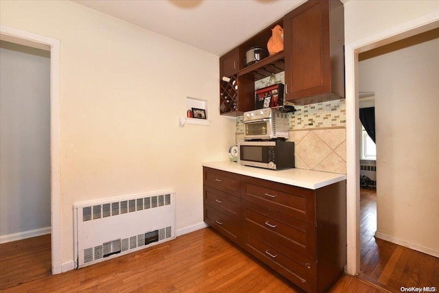 kitchen featuring decorative backsplash, hardwood / wood-style floors, and radiator