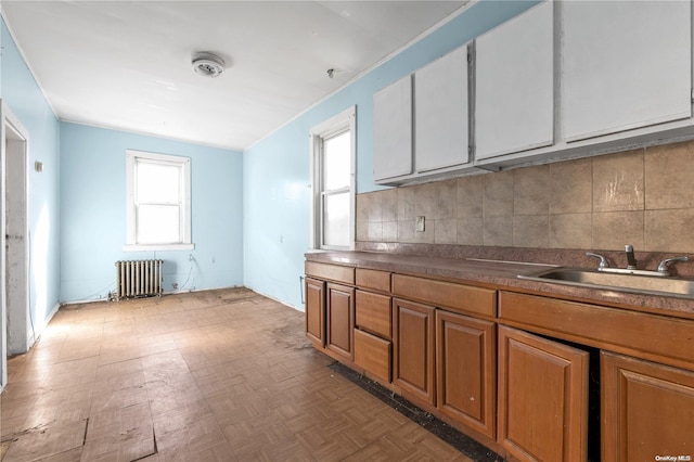 kitchen with parquet floors, sink, radiator, and tasteful backsplash