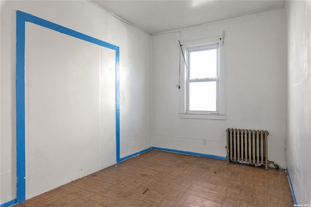 unfurnished room featuring parquet flooring and radiator