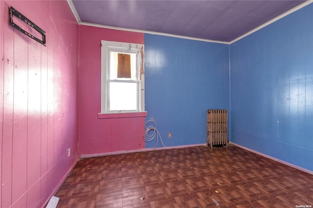 empty room featuring dark parquet flooring, crown molding, and wood walls