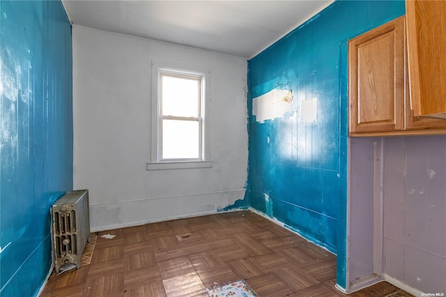 spare room featuring dark parquet flooring and radiator heating unit