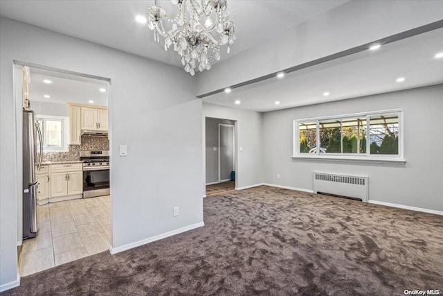 unfurnished living room featuring radiator, a chandelier, and light colored carpet