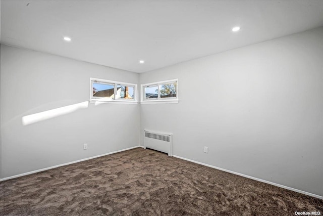 empty room featuring carpet flooring and radiator heating unit