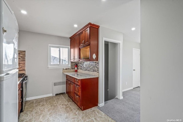 kitchen featuring light carpet, backsplash, white refrigerator, radiator heating unit, and stainless steel stove