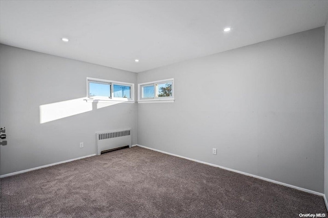 spare room featuring carpet and radiator heating unit