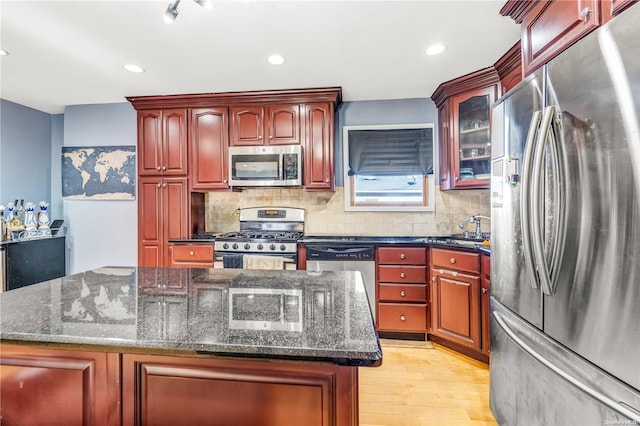 kitchen with a center island, light hardwood / wood-style floors, stainless steel appliances, and dark stone counters