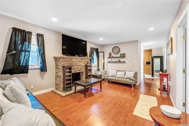 living room with hardwood / wood-style floors and a stone fireplace