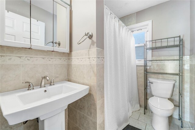 bathroom featuring tile patterned floors, sink, a shower with shower curtain, toilet, and tile walls