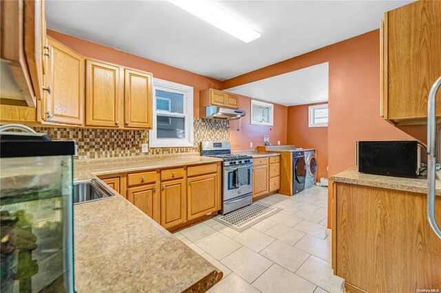 kitchen with washer and dryer, light tile patterned floors, backsplash, and stainless steel gas range