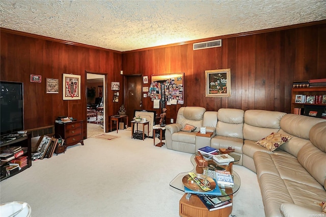 living room featuring wood walls, crown molding, carpet floors, and a textured ceiling