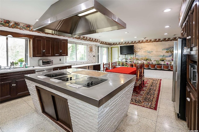 kitchen with black electric stovetop, wall chimney exhaust hood, sink, a center island, and stainless steel refrigerator