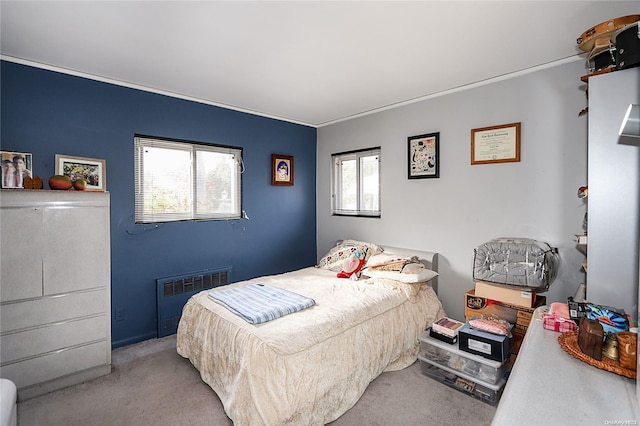 bedroom with multiple windows, light colored carpet, and radiator