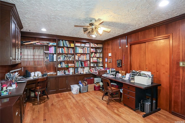 office with ceiling fan, wood walls, a textured ceiling, and light wood-type flooring