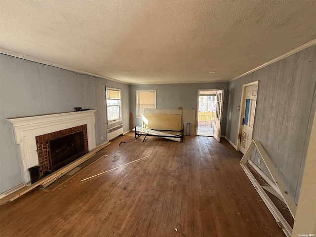 unfurnished living room featuring a textured ceiling, a healthy amount of sunlight, dark wood-type flooring, and a brick fireplace