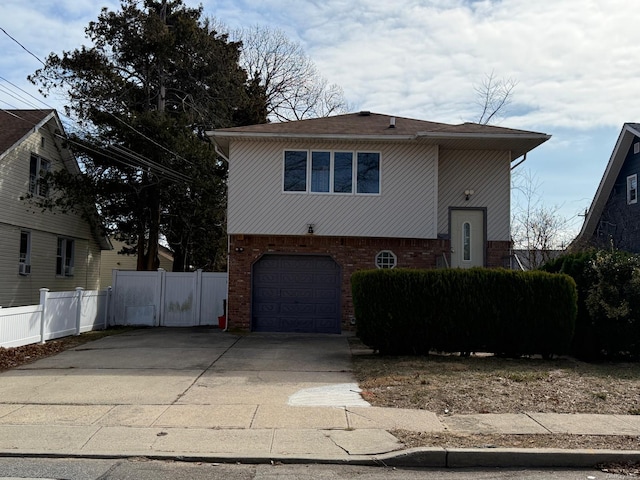 view of front of property with concrete driveway, an attached garage, fence, and brick siding