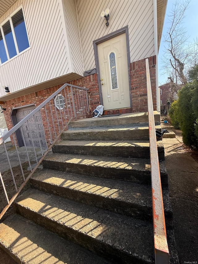 property entrance featuring a garage and brick siding