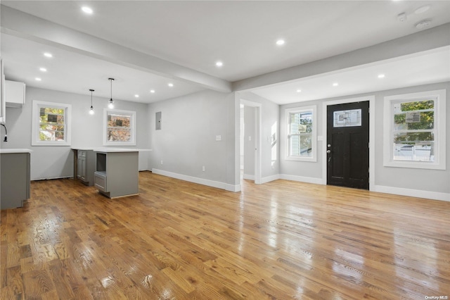 interior space featuring gray cabinetry, pendant lighting, light hardwood / wood-style flooring, beamed ceiling, and white cabinetry