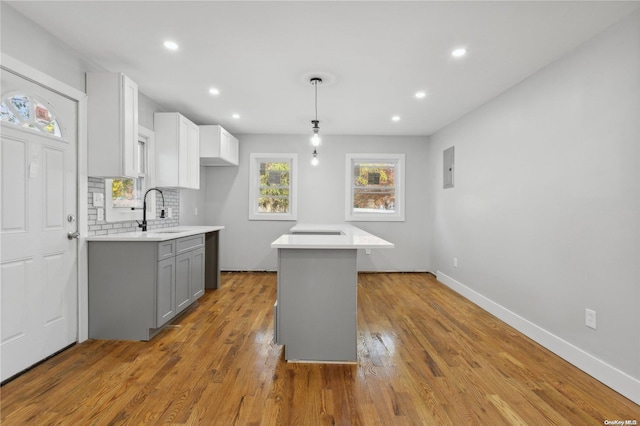 kitchen featuring backsplash, sink, decorative light fixtures, gray cabinets, and a kitchen island