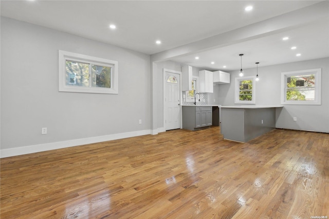 kitchen featuring backsplash, white cabinets, gray cabinets, decorative light fixtures, and light hardwood / wood-style floors