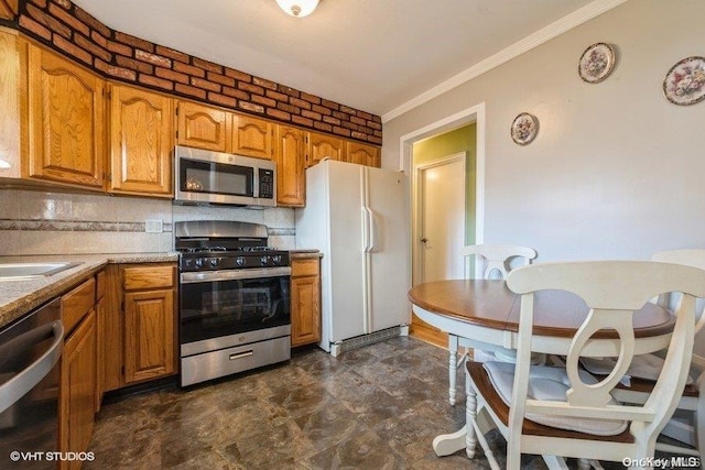 kitchen with sink, brick wall, backsplash, crown molding, and appliances with stainless steel finishes