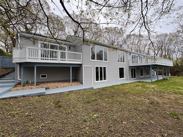 rear view of property with a lawn, a wooden deck, stairway, and a patio