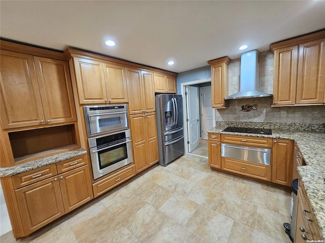 kitchen with decorative backsplash, light stone countertops, stainless steel fridge, a warming drawer, and wall chimney exhaust hood