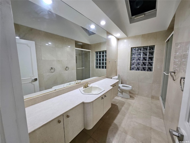 bathroom featuring tile walls, a shower stall, vanity, tile patterned floors, and toilet