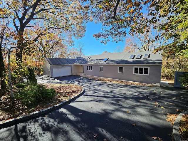 single story home featuring an attached garage and aphalt driveway