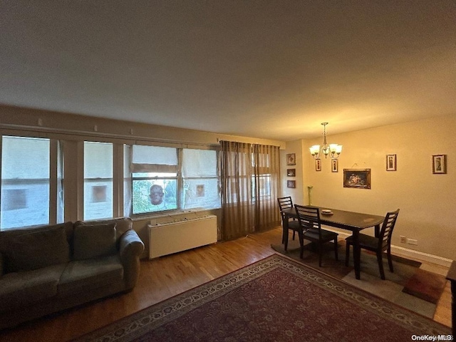 dining area featuring wood-type flooring, an inviting chandelier, and radiator