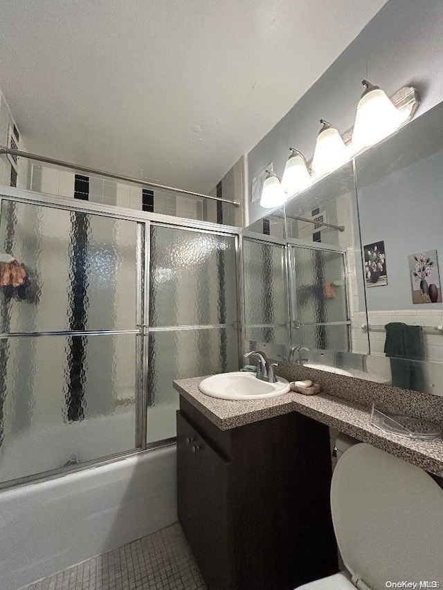 full bathroom with tile patterned floors, shower / bath combination with glass door, vanity, and toilet