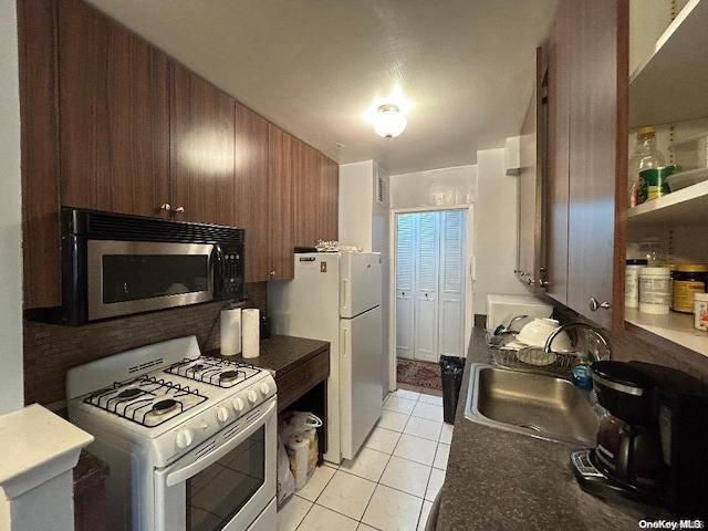 kitchen featuring sink, light tile patterned floors, and white appliances