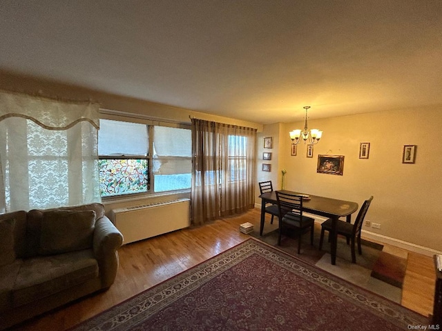 dining space featuring hardwood / wood-style flooring, radiator, and an inviting chandelier