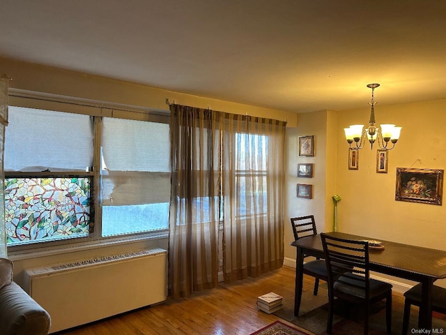 dining room featuring a chandelier, radiator heating unit, and hardwood / wood-style flooring