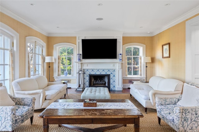 living room featuring a healthy amount of sunlight, ornamental molding, and a tiled fireplace