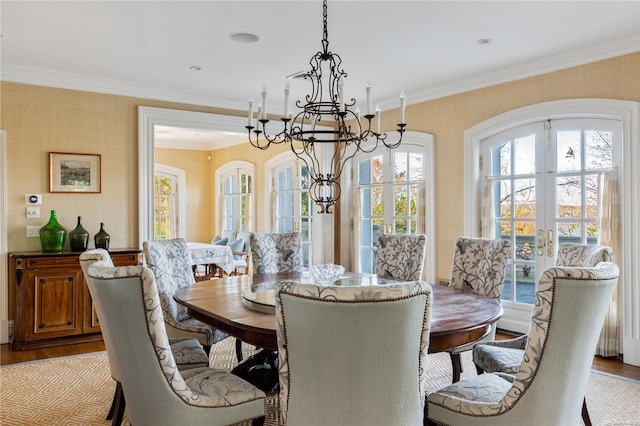 dining space featuring a chandelier, french doors, ornamental molding, and light wood-type flooring