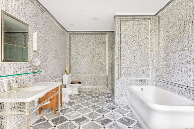 bathroom with a washtub, toilet, a bidet, and tile walls