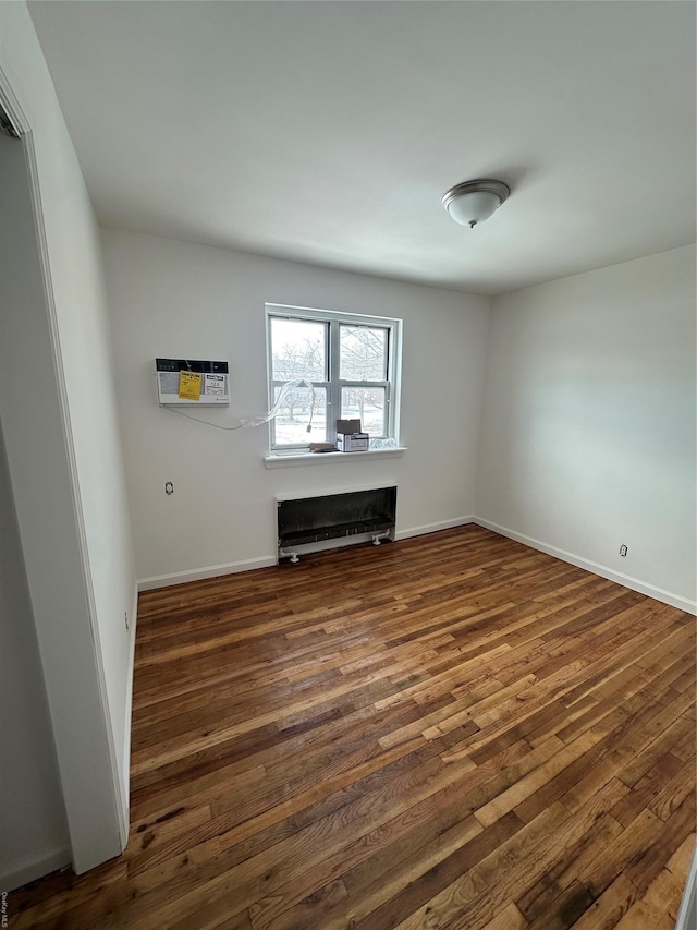 spare room featuring baseboards, dark wood finished floors, and a wall mounted air conditioner