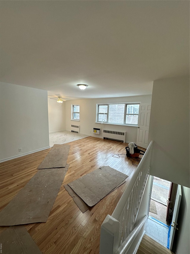 bonus room featuring radiator heating unit, ceiling fan, and light hardwood / wood-style flooring