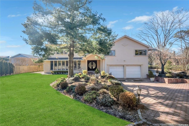 view of front of home featuring a sunroom, a garage, and a front yard