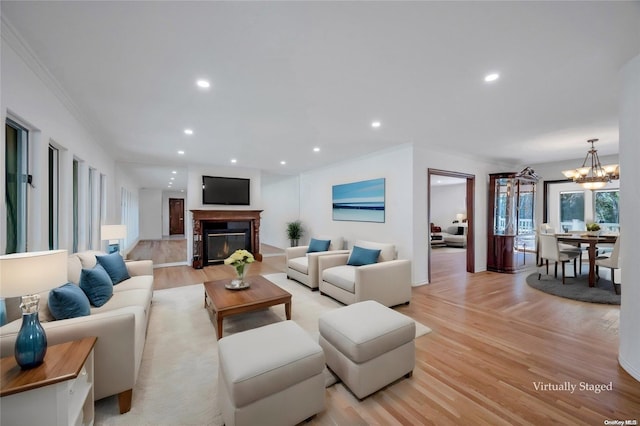 living room featuring light wood-type flooring, an inviting chandelier, and ornamental molding