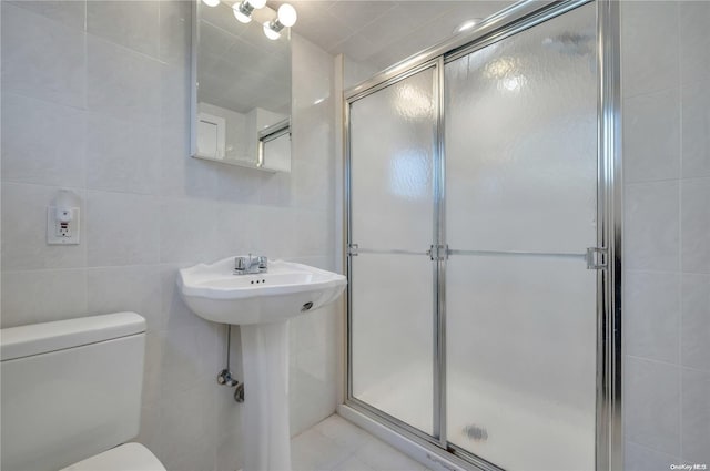 bathroom with an enclosed shower, tile patterned flooring, toilet, and tile walls