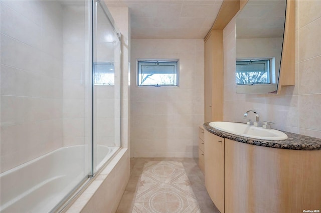 bathroom featuring vanity, tiled shower / bath combo, tile walls, and tile patterned flooring