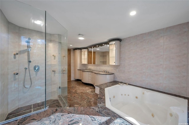 bathroom featuring vanity, plus walk in shower, and tile walls