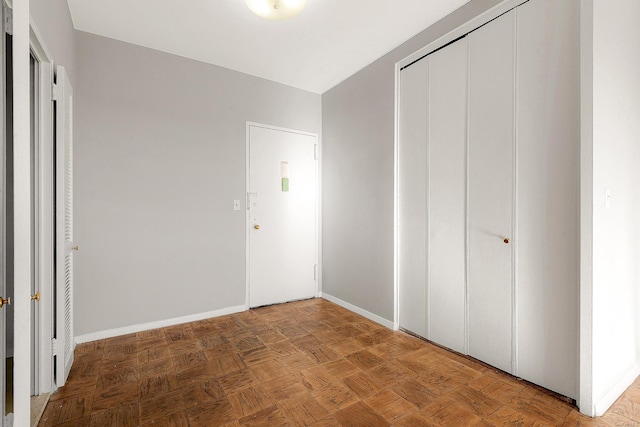 unfurnished bedroom featuring parquet flooring and a closet