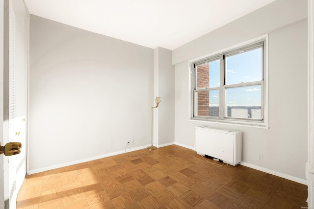 spare room featuring parquet flooring and radiator