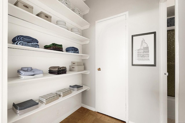 spacious closet with dark parquet flooring