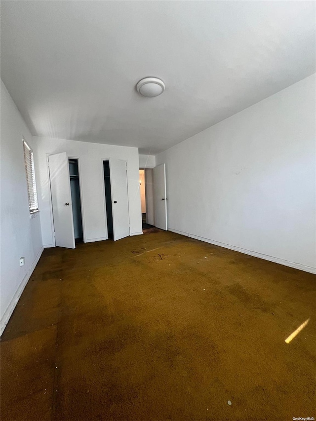 138-25 31st Dr Unit 3E, Flushing, NY 11354 - unfurnished bedroom with dark colored carpet, baseboards, and multiple closets