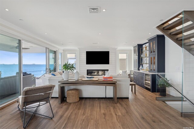 living room with dark hardwood / wood-style floors, crown molding, a water view, and a fireplace