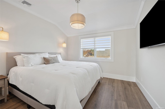 bedroom featuring ornamental molding, lofted ceiling, and hardwood / wood-style flooring